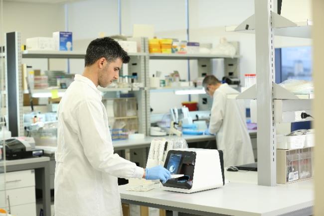 עובד מעבדה בוחן דגימה של חולה כדי לזהות אם מקור הזיהום הוא חיידקי או ויראלי טכנולוגיה שפותחה על ידי חברת MeMed